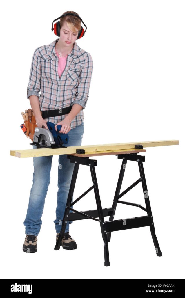 Femme concentrée portant un casque anti-bruit et utilisant une scie circulaire sur une planche de bois, représentant un bricoleur amateur.